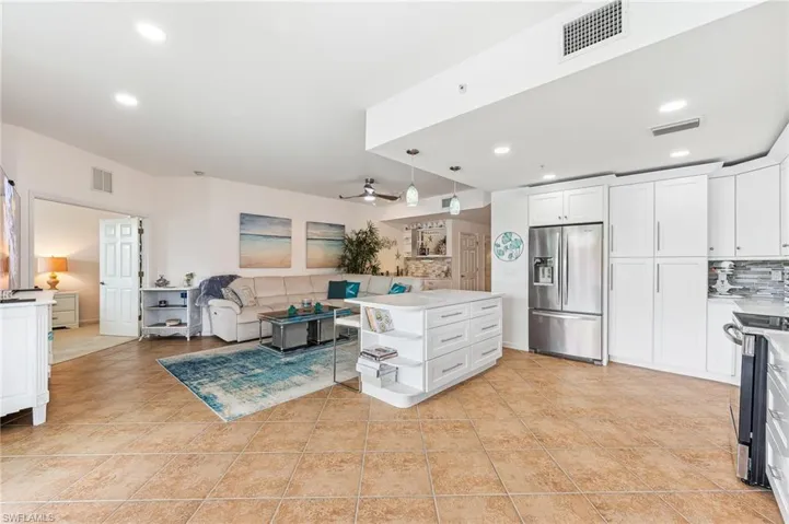 Kitchen with tasteful backsplash, white cabinetry, appliances with stainless steel finishes, and light tile patterned flooring