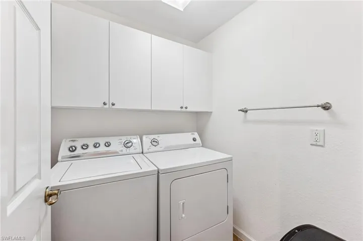 Clothes washing area featuring cabinets and washer and dryer