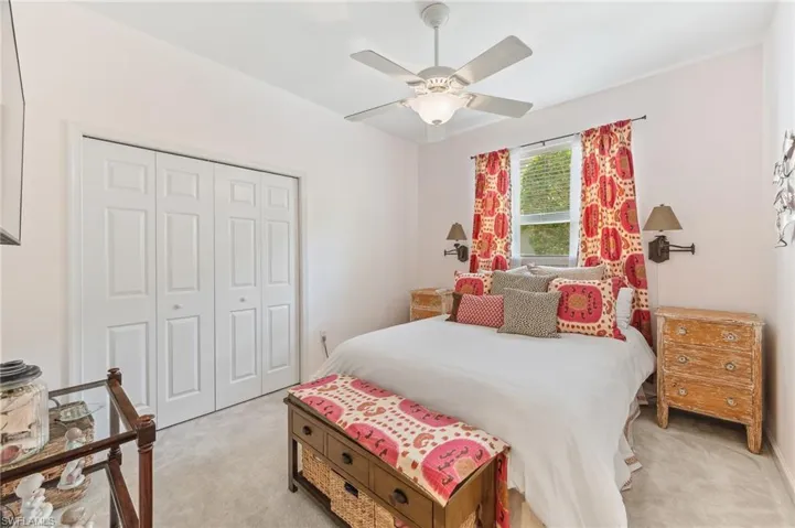 Carpeted bedroom with ceiling fan and a closet