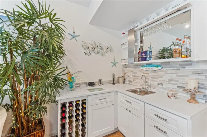 Bar featuring white cabinets, sink, and tasteful backsplash