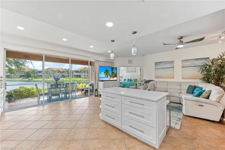 Kitchen featuring decorative light fixtures, vaulted ceiling, white cabinets, a water view, and ceiling fan
