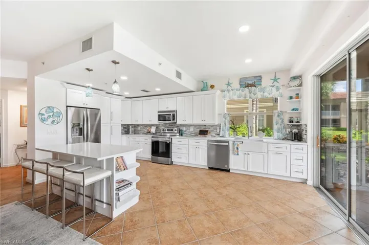 Kitchen featuring white cabinetry, appliances with stainless steel finishes, backsplash, and hanging light fixtures