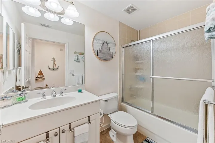 Full bathroom featuring shower / bath combination with glass door, tile patterned floors, vanity, and toilet