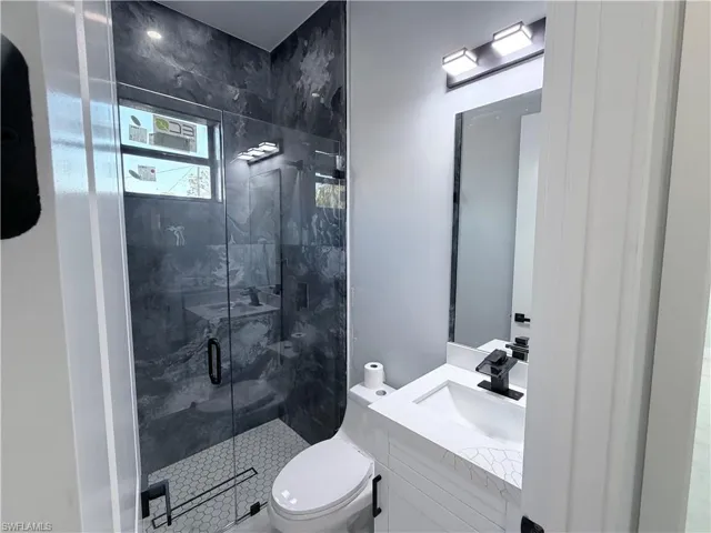 Full bathroom featuring vanity and a marble finish shower