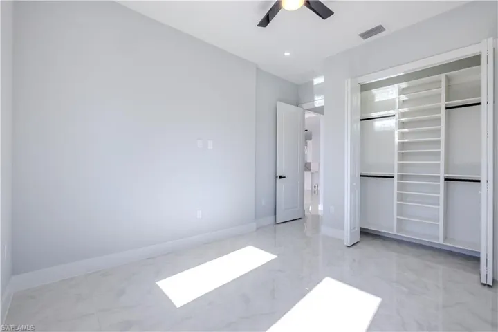 Unfurnished bedroom featuring light marble finish flooring, a closet, and a ceiling fan