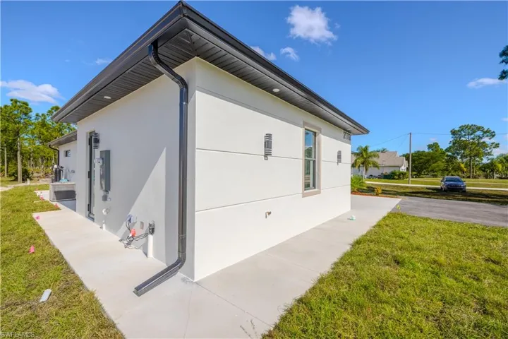 View of side of property featuring a lawn, stucco siding, and lawncare items