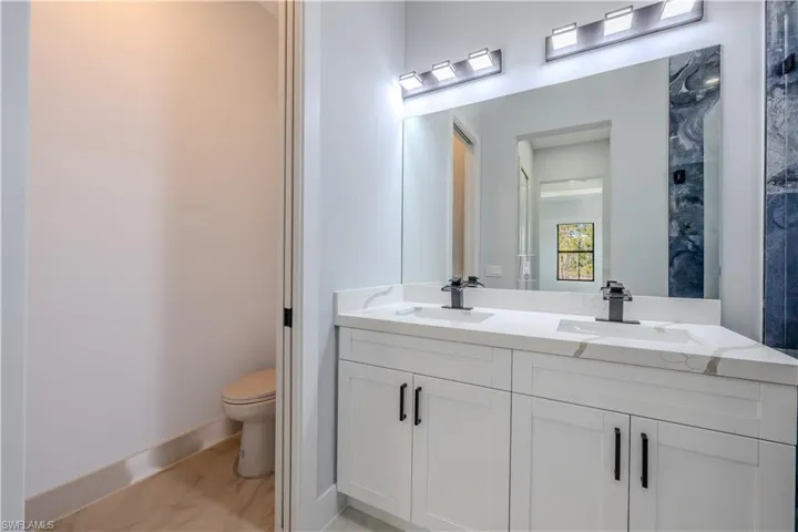 Full bathroom featuring toilet and double vanity