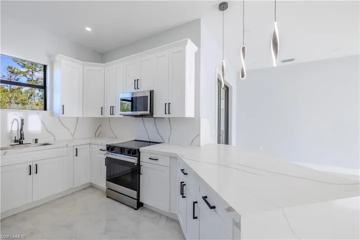 Kitchen with stainless steel appliances, pendant lighting, white cabinets, light stone counters, and recessed lighting