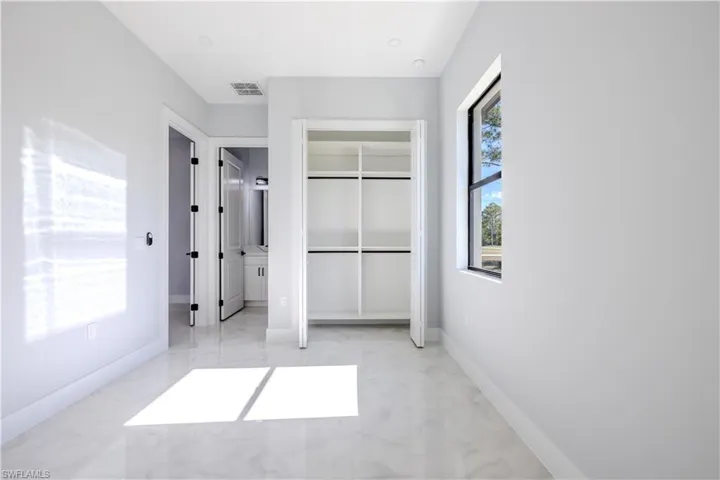 Unfurnished bedroom with a closet, light marble finish floors, and ensuite bath