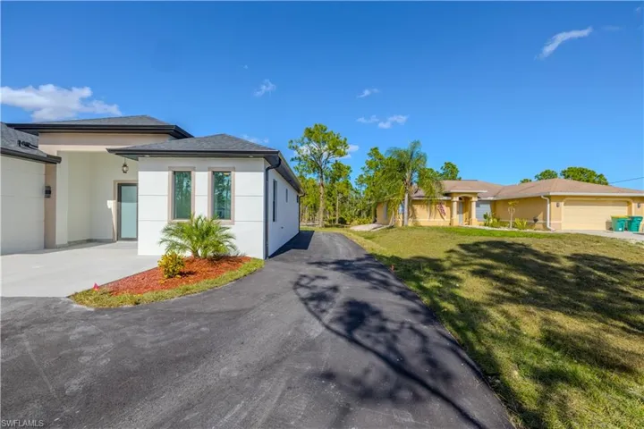 View of front of property with a front lawn, stucco siding, driveway, and a garage