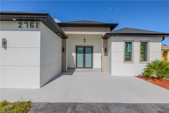 Doorway to property with stucco siding, french doors, and a shingled roof