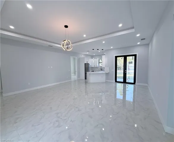 Unfurnished living room with french doors, recessed lighting, and light marble finish floors
