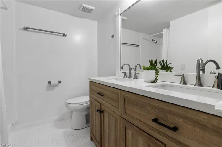 Master Bathroom with double sink vanity, tile flooring, and toilet