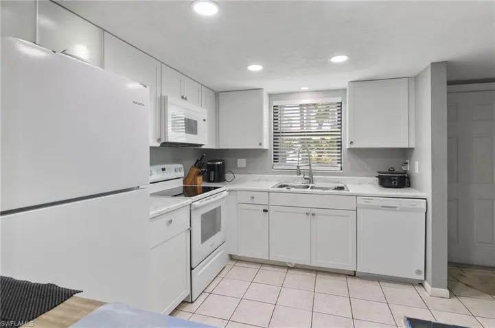 Kitchen with sink, white cabinetry, white appliances, and light tile floors