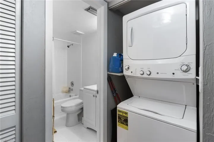 Laundry area with tile flooring and stacked washer / drying machine