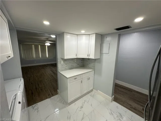 Kitchen with light countertops, tasteful backsplash, marble finish floor, visible vents, and white cabinets