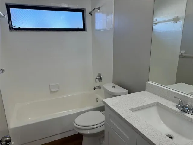 Full bathroom featuring vanity, toilet, tiled shower / bath combo, and wood-type flooring