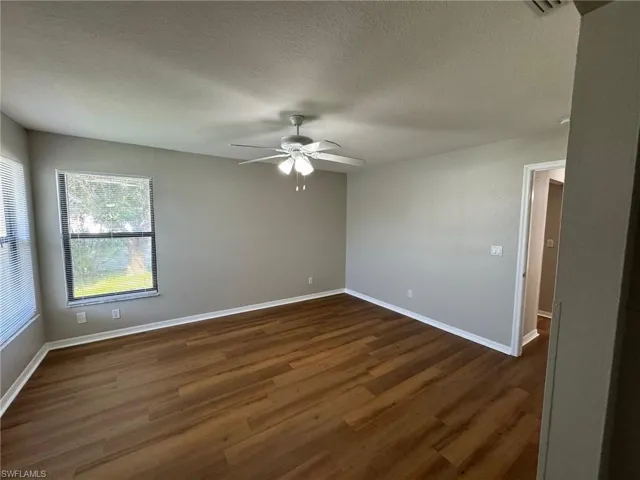Master bedroom with a textured ceiling, dark wood-type flooring, and ceiling fan