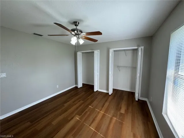 Guest bedroom 2 featuring multiple closets, dark hardwood / wood-style flooring, and ceiling fan