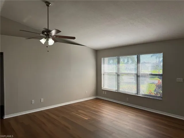 Living room featuring a textured ceiling, lofted ceiling, ceiling fan, and dark hardwood / wood-style floors