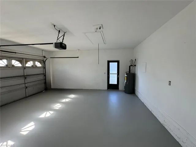 Garage featuring a garage door opener and water heater