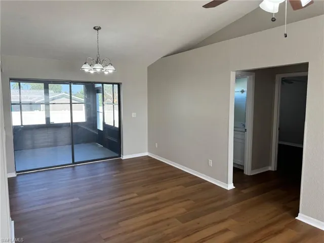 Dining room featuring lofted ceiling, ceiling fan with notable chandelier, and dark hardwood / wood-style flooring