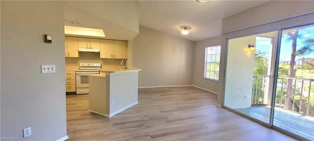 Kitchen with white range with electric stovetop, white cabinetry, lofted ceiling, sink, and light wood-type flooring