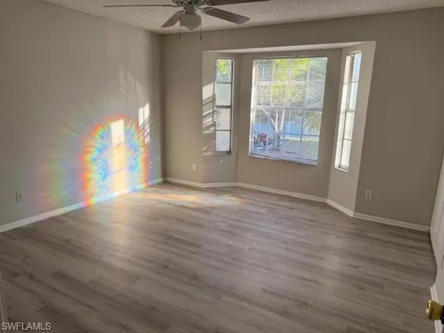 Unfurnished room with hardwood / wood-style floors, a textured ceiling, and ceiling fan