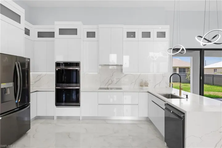 Kitchen featuring white cabinets, decorative light fixtures, black appliances, and sink