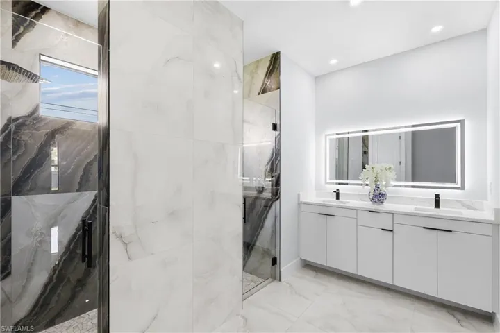 Bathroom with double vanity, tile patterned floors, and tiled shower