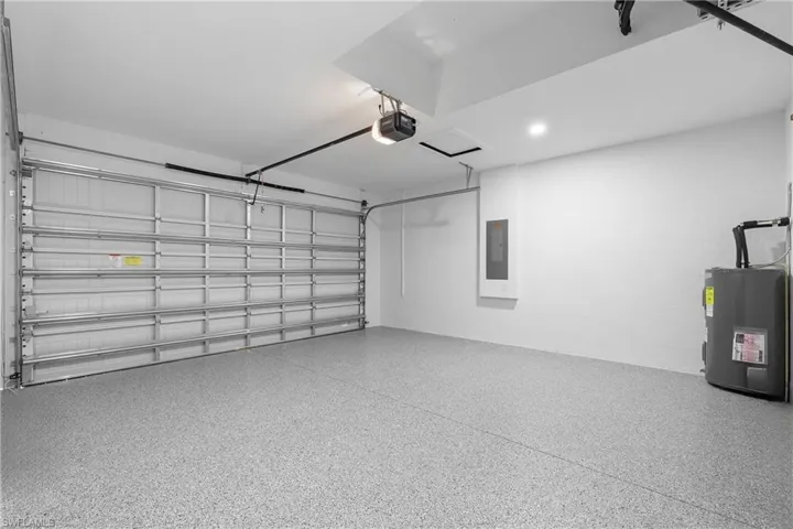 Garage featuring water heater, electric panel, and a garage door opener