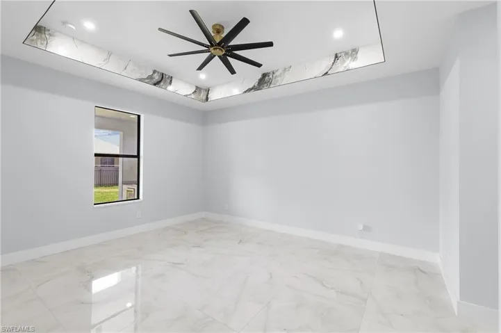 Spare room with a tray ceiling, light tile patterned floors, and ceiling fan