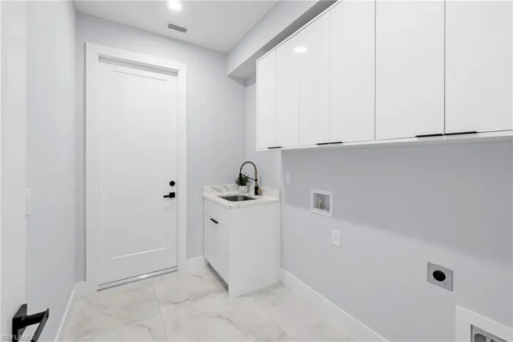 Laundry room featuring hookup for an electric dryer, sink, cabinets, light tile patterned floors, and washer hookup