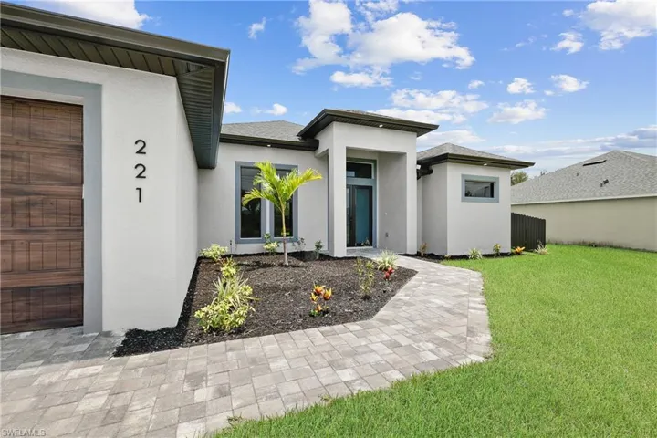 View of exterior entry featuring a garage and a lawn