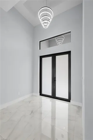 Empty room featuring a chandelier, french doors, and light tile patterned floors