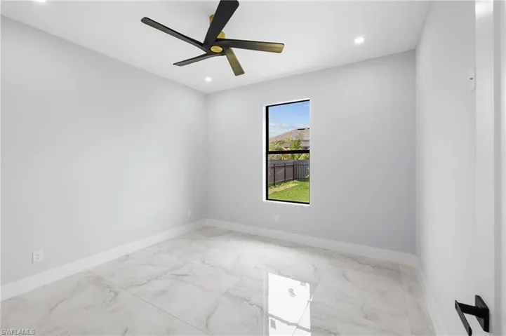 Empty room with ceiling fan and light tile patterned floors