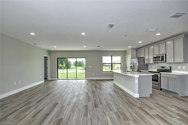 Kitchen with appliances with stainless steel finishes, sink, gray cabinetry, and light hardwood / wood-style floors