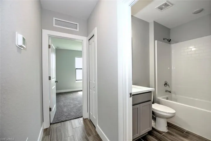 Full bathroom with tiled shower / bath, vanity, toilet, and hardwood / wood-style flooring