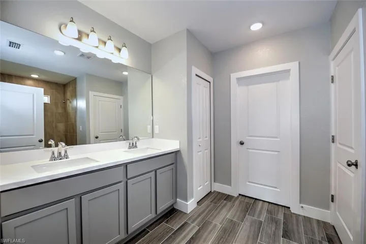 Bathroom with hardwood / wood-style floors, tiled shower, and vanity