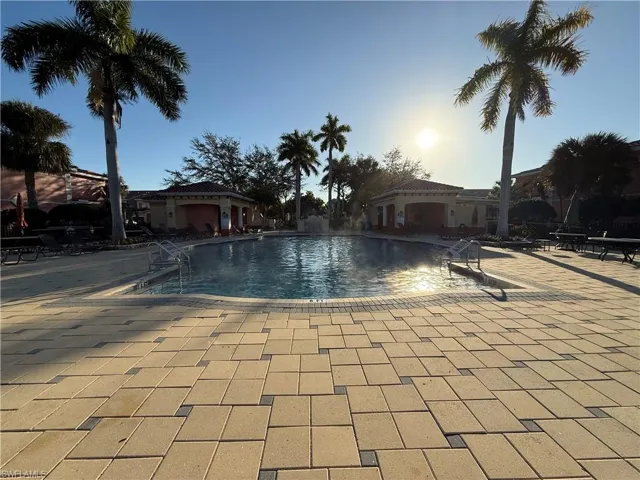 Pool at dusk featuring a community pool and a patio area