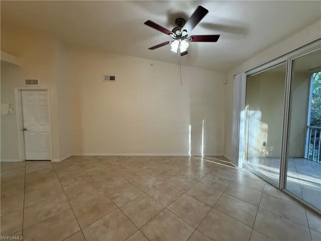 Unfurnished room with ceiling fan, vaulted ceiling, and light tile patterned floors