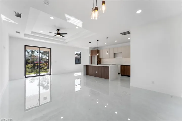Unfurnished living room with sink, a tray ceiling, and ceiling fan