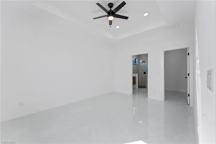 Unfurnished room with ceiling fan and a tray ceiling