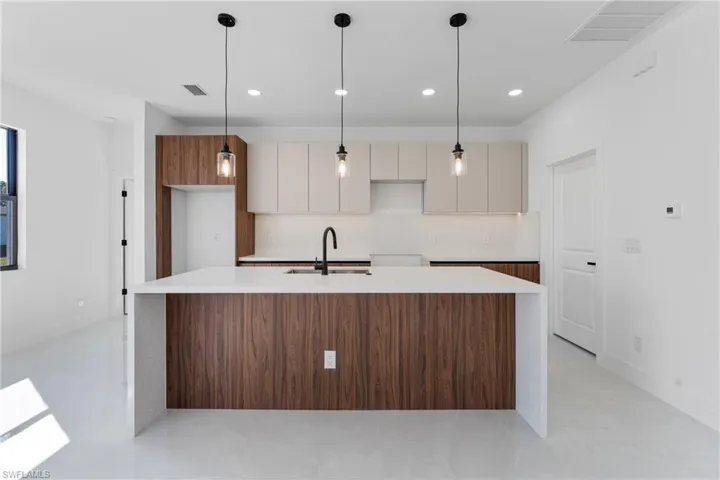 Kitchen featuring hanging light fixtures, white cabinetry, sink, and decorative backsplash