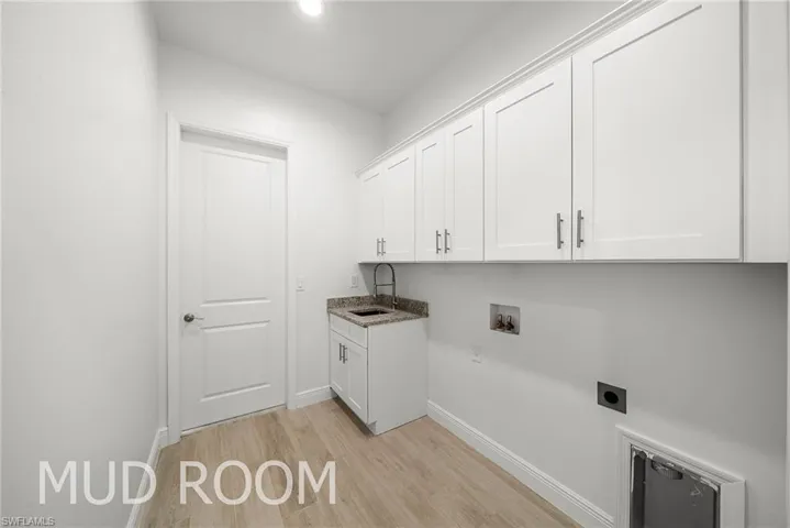 Clothes washing area with cabinets, electric dryer hookup, light hardwood / wood-style flooring, washer hookup, and sink