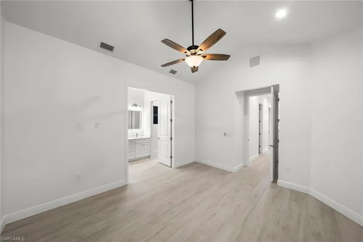 Empty room featuring lofted ceiling, ceiling fan, and light hardwood / wood-style floors