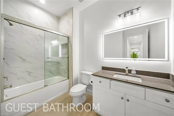 Full bathroom with combined bath / shower with glass door, vanity, toilet, and hardwood / wood-style floors