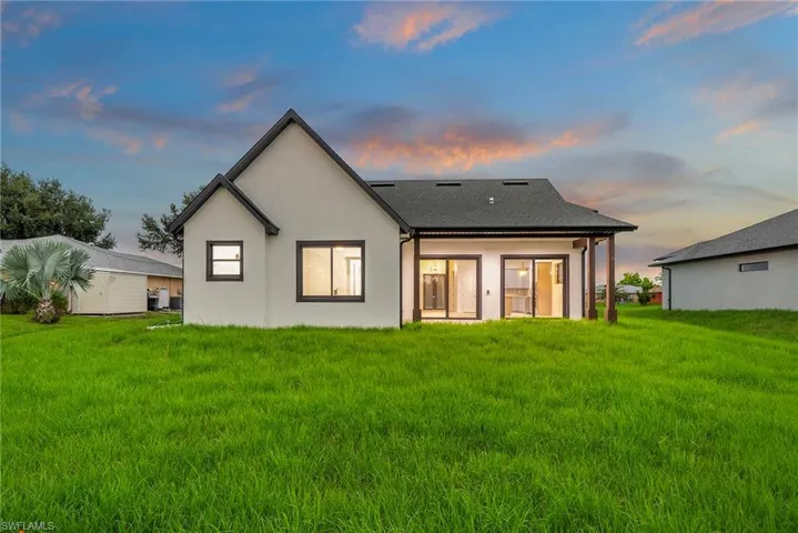 Back house at dusk with a lawn