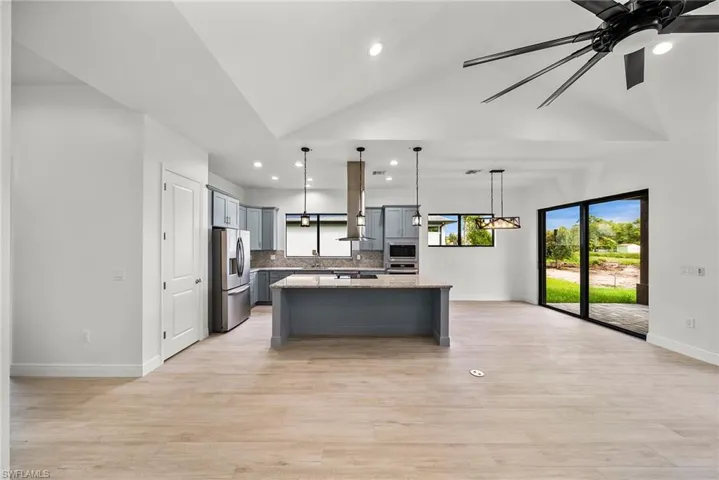 Kitchen featuring hanging light fixtures, a center island, stainless steel appliances, gray cabinets, and ceiling fan