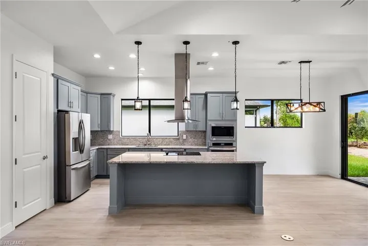 Kitchen featuring light stone counters, plenty of natural light, a kitchen island, and stainless steel appliances